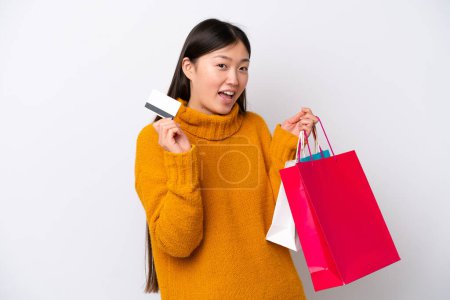 Téléchargez les photos : Jeune femme chinoise isolée sur fond blanc tenant des sacs à provisions et une carte de crédit - en image libre de droit