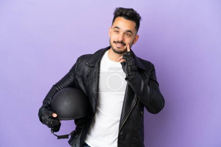Téléchargez les photos : Jeune homme avec un casque de moto isolé sur fond violet penser une idée tout en levant les yeux - en image libre de droit