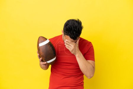 Foto de Joven hombre caucásico jugando rugby aislado sobre fondo amarillo con expresión cansada y enferma - Imagen libre de derechos