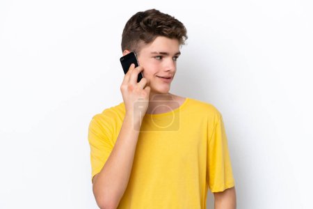 Téléchargez les photos : Adolescent l'homme à l'aide de téléphone mobile isolé sur fond blanc regarder côté - en image libre de droit