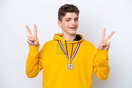 Foto de Adolescente ruso hombre con medallas aisladas sobre fondo blanco mostrando signo de victoria con ambas manos - Imagen libre de derechos