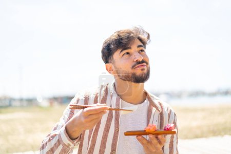 Photo for Handsome Arab man at outdoors holding sashimi - Royalty Free Image