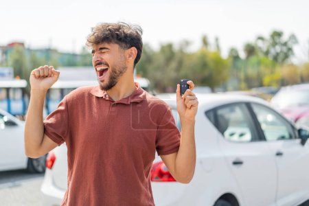 Foto de Joven árabe guapo al aire libre sosteniendo las llaves del coche y celebrando una victoria - Imagen libre de derechos