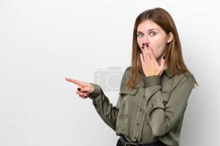 Foto de Joven mujer inglesa aislada sobre fondo blanco con expresión sorpresa mientras señala lado - Imagen libre de derechos