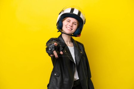 Téléchargez les photos : Jeune femme anglaise avec un casque de moto isolé sur fond jaune pointant vers l'avant avec une expression heureuse - en image libre de droit