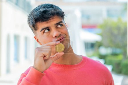 Photo for Young hispanic man at outdoors holding a Bitcoin - Royalty Free Image