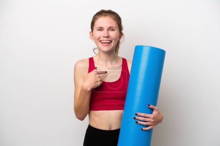 Téléchargez les photos : Jeune femme anglaise sportive allant à des cours de yoga tout en tenant un tapis isolé sur fond blanc avec expression faciale surprise - en image libre de droit