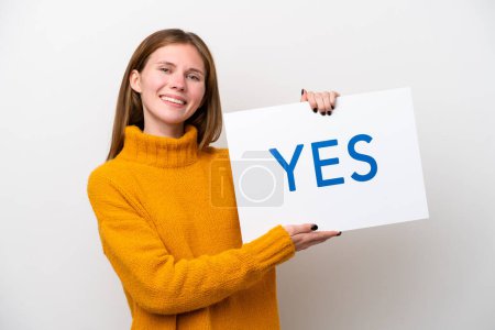 Téléchargez les photos : Jeune Anglaise isolée sur fond blanc tenant une pancarte avec du texte OUI avec une expression heureuse - en image libre de droit
