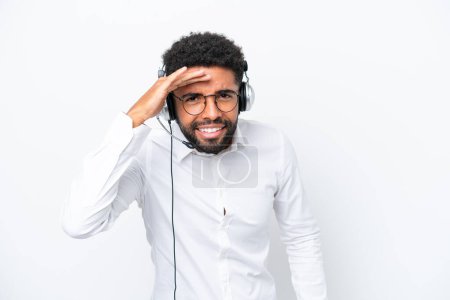 Telemarketer Brazilian man working with a headset isolated on white background looking far away with hand to look something