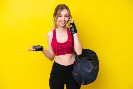 Photo for Young sport caucasian woman with sport bag isolated background keeping a conversation with the mobile phone with someone - Royalty Free Image