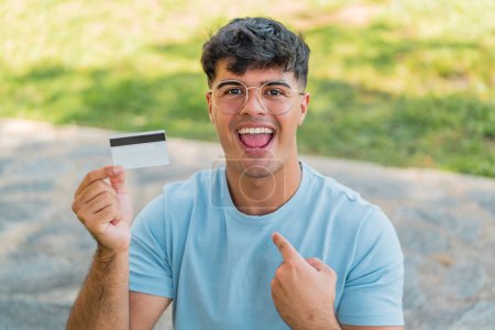 Photo for Young hispanic man holding a credit card at outdoors with surprise facial expression - Royalty Free Image