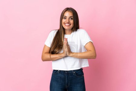 Photo for Young Uruguayan woman isolated on pink background keeps palm together. Person asks for something - Royalty Free Image