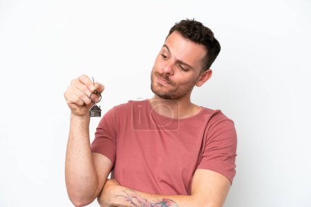 Photo for Young caucasian man holding home keys isolated on white background with sad expression - Royalty Free Image