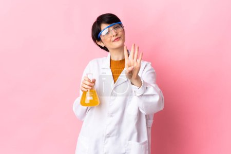 Téléchargez les photos : Jeune femme scientifique isolée sur fond rose heureuse et comptant quatre avec les doigts - en image libre de droit