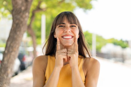 Téléchargez les photos : Jeune femme à l'extérieur souriant avec une expression heureuse et agréable - en image libre de droit