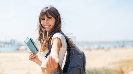 Foto de Mujer joven al aire libre sosteniendo un pasaporte y haciendo el gesto que viene - Imagen libre de derechos