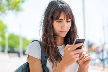 Téléchargez les photos : Jeune femme à l'extérieur en utilisant un téléphone mobile - en image libre de droit
