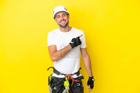 Photo for Young rock- climber man isolated on yellow background pointing to the side to present a product - Royalty Free Image