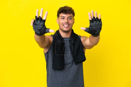 Foto de Joven deportista caucásico con toalla aislada sobre fondo amarillo contando nueve con dedos - Imagen libre de derechos