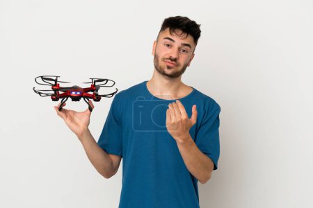 Photo for Man holding a drone isolated on white background inviting to come with hand. Happy that you came - Royalty Free Image