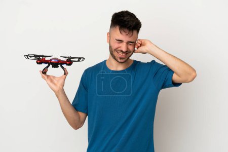Photo for Man holding a drone isolated on white background frustrated and covering ears - Royalty Free Image