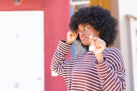 Photo for African American girl holding home keys at outdoors having doubts and with confuse face expression - Royalty Free Image