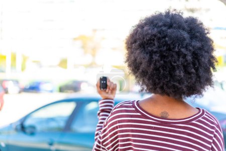 Téléchargez les photos : Afro-américaine fille tenant des clés de voiture à l'extérieur en position arrière - en image libre de droit