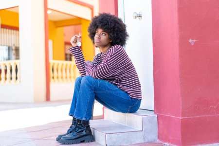 Téléchargez les photos : Afro-américaine fille tenant maison clés à l'extérieur - en image libre de droit