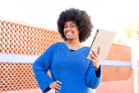Photo for African American girl at outdoors holding a tablet with happy expression - Royalty Free Image