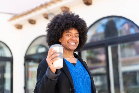 Photo for African American girl holding a take away coffee at outdoors with happy expression - Royalty Free Image