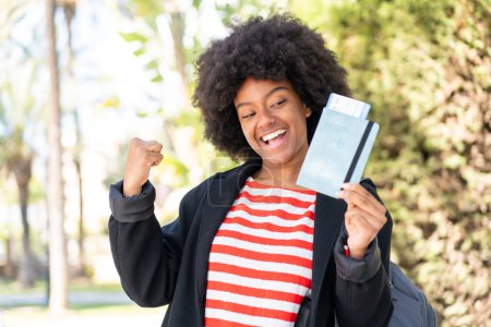 Téléchargez les photos : Afro-Américaine tenant un passeport en plein air célébrant une victoire - en image libre de droit