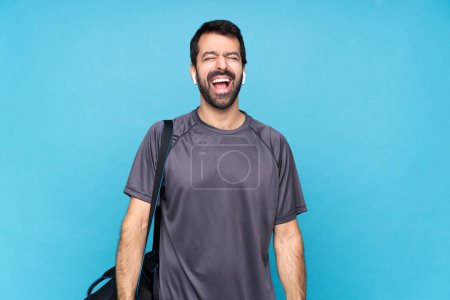 Photo for Young sport man with beard over isolated blue background shouting to the front with mouth wide open - Royalty Free Image