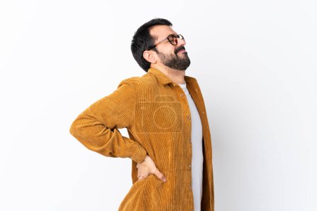 Foto de Hombre guapo caucásico con barba vistiendo una chaqueta de pana sobre fondo blanco aislado que sufre de dolor de espalda por haber hecho un esfuerzo - Imagen libre de derechos