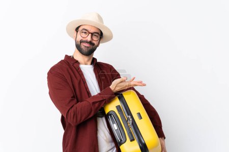 Photo for Traveler man man with beard holding a suitcase over isolated white background presenting an idea while looking smiling towards - Royalty Free Image