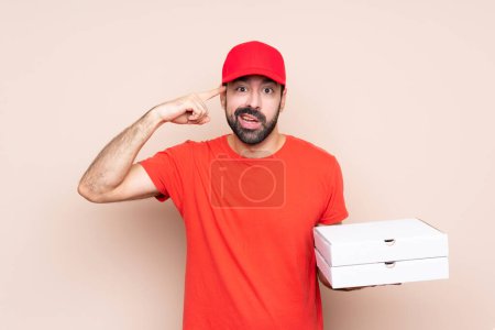 Téléchargez les photos : Jeune homme tenant une pizza sur fond isolé faisant le geste de folie mettant le doigt sur la tête - en image libre de droit