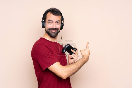 Foto de Hombre jugando con un controlador de videojuegos sobre una pared aislada apuntando hacia atrás - Imagen libre de derechos