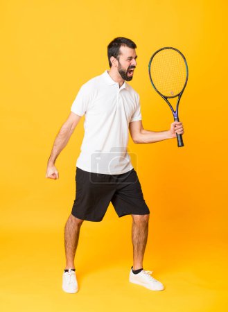 Téléchargez les photos : Plan complet de l'homme sur fond jaune isolé jouant au tennis et célébrant une victoire - en image libre de droit