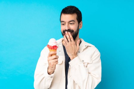Téléchargez les photos : Jeune homme avec une crème glacée cornet sur fond bleu isolé - en image libre de droit
