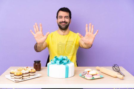 Foto de Hombre en una mesa con un gran pastel contando diez con los dedos - Imagen libre de derechos