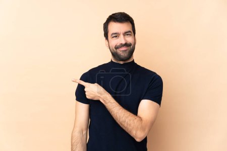 Photo for Caucasian handsome man over isolated background pointing to the side to present a product - Royalty Free Image