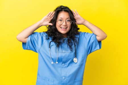 Téléchargez les photos : Jeune chirurgien médecin asiatique femme isolée sur fond jaune avec expression surprise - en image libre de droit
