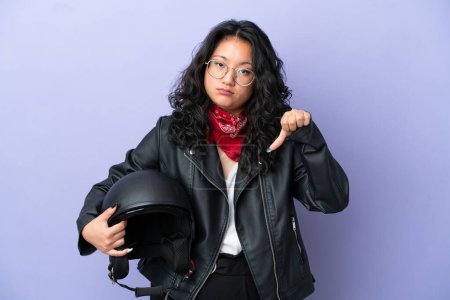 Photo for Young asian woman with a motorcycle helmet isolated on purple background showing thumb down with negative expression - Royalty Free Image