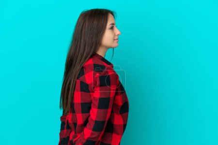 Photo for Young Ukrainian woman isolated on blue background in back position and looking back - Royalty Free Image