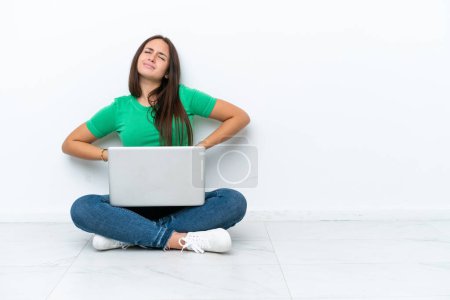 Photo for Young Ukrainian woman with a laptop sitting on floor suffering from backache for having made an effort - Royalty Free Image