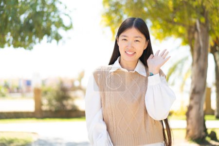 Photo for Pretty Chinese woman at outdoors saluting with hand with happy expression - Royalty Free Image