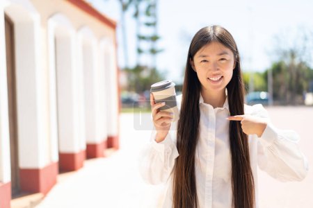 Pretty Chinese woman holding a take away coffee at outdoors with surprise facial expression