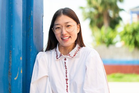 Téléchargez les photos : Jeune femme chinoise à l'extérieur Avec une expression heureuse - en image libre de droit