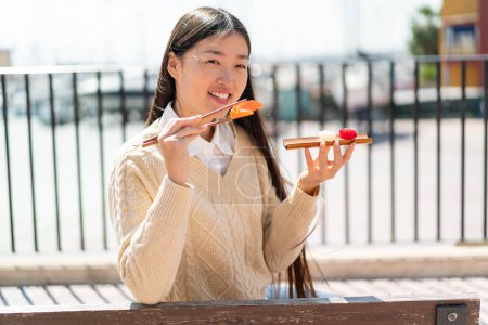 Foto de Joven mujer china sosteniendo sashimi al aire libre - Imagen libre de derechos