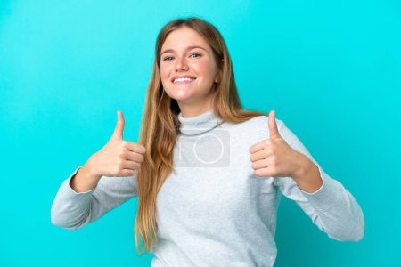 Photo for Young blonde woman isolated on blue background giving a thumbs up gesture - Royalty Free Image