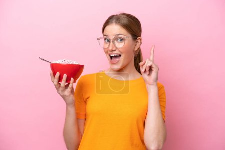 Photo for Young caucasian woman holding a bowl of cereals isolated on pink background pointing up a great idea - Royalty Free Image